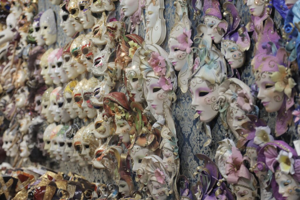 Various carnival Venetian masks with floral adornment placed on wall in local market